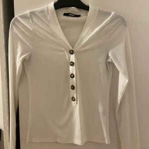 Vit topp med knappar  - Säljer en snygg vit topp med bruna/svarta knappar från Bikbok. I storlek S✨