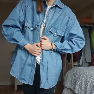 Jeansskjorta - Jeansskjorta med tryckknappar från Lacrozz, knappt använd. Strl S, men sitter mer som en M/L. Samma passform och utseende som Levi's (säljer även en Levi's-skjorta). Pris 200kr plus frakt.
