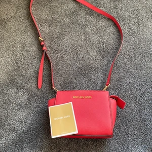 Super snygg ceris Michael kors Väska. - Super snygg ceris (rosa/orange) färgad handväska. Den är rymlig för sin storlek och har som en inbyggd plånbok inuti. Den har avtagbara band och reglerbara band. 100% äkta - har dustbag och äkthetsbevis, som syns på bilden. Köpt för några år sedan men får tyvärr ingen nytta av den längre! Skriv för pris och leverans alternativ! Nypris: ca 3000kr