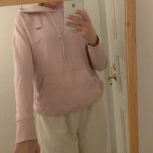 Hoodie från Levis - Jättefin ljuslila hoodie från Levis. Köpt från Carlings för 800 kronor. Använd cirka 5 gånger, då jag inte så ofta fått tillfälle. Skick 10/10. Storlek xs men passar bra på mig som är 173 cm och brukar ha s. 