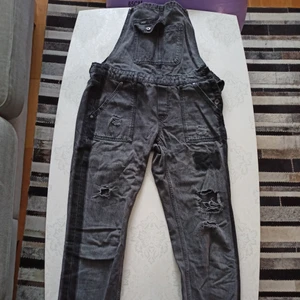 Grå/ svarta dungarees - Ett par grå/svarta hängselbyxor i jeansmaterial ifrån Superdry med revor på benen. Byxorna är väl "ingångna" men har inga större defekter, endast extra slit på revorna. Rekommenderas inte för längre personer då de sitter jättekort på mig som är 185 cm. 