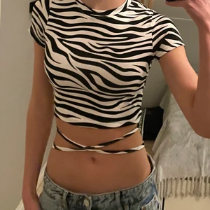 Zebramönstrad T-shirt med öppen rygg - Zebramönstrad T-shirt med öppen rygg, den går att knyta på olika sätt. Den är oanvänd, endast testad med lappen kvar. I ett väldigt stretchigt material. Den är från new yorker men köpt i Kroatien. T-shirten är i storlek xs men passar även S.