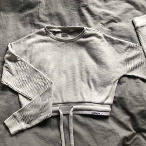 Gymshark tröja - Tröja från gymshark i storlek XS. Tröjan är ljusgrå och har ett resår band längst ner.                                        Köparen står för frakten!