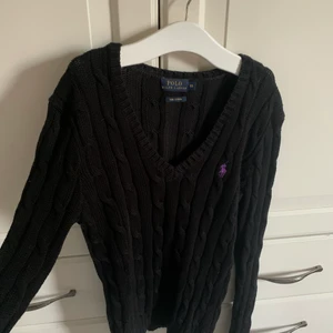 Svart kabelstickad Ralph Lauren tröja med lila märke  - Storlek Xs, och är i vädligt bra sick och väldigt fin. Endast använd några gånger. Köpt för 1500 kr. Kan mötas i Stockholm annars står köparen för frakten❤️