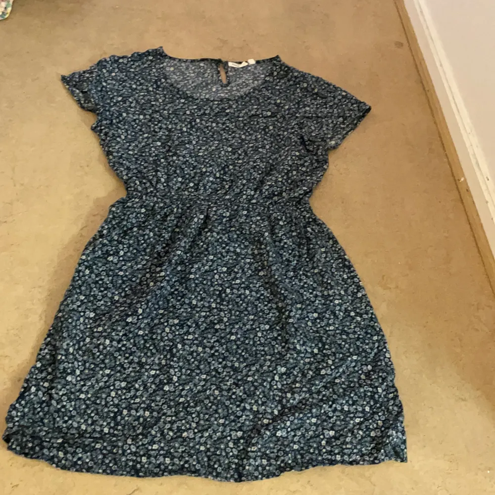 En blå blommig klänning i strl:158. Är använd fåtals gånger och är i bra skick. . Klänningar.