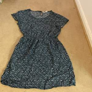En blå blommig klänning i strl:158. Är använd fåtals gånger och är i bra skick. 