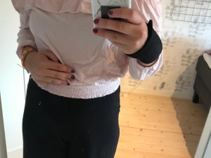 Tröja - En rosa långärmad tröja. Med volanger och hål vid axlarna.