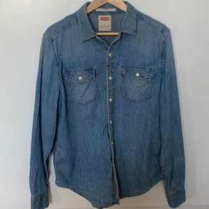 Blå Levi’s skjorta - En Levi’s skjorta i storlek M (herr, men funkar lika bra till tjejer). Original pris ca 700kr men säljes för 150 ink. frakt. I bra skick men ett ytterst litet hål i högra ärm (se bild). Vid frågor eller fler bilder kontakta privat. 
