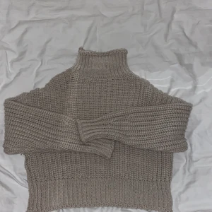 Stickad polotröja  - Beige stickad tröja med hög krage som också går att vika ner. Sitter lite tajtare i midjan och pösigare över och i armarna.