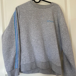 Grå sweatshirt med blåa och rosa detaljer - Sweatshirt med rosa/blått band på ärmarna från Devier, storlek S