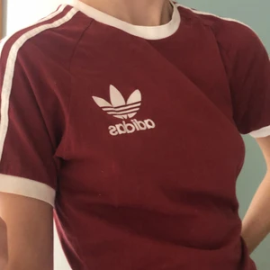 Adidas T-shirt  - Vinröd T-shirt köpt i Köpenhamn för några år sedan men som jag inte fått användning för på ett bra tag. Den är i gott skick utan hål eller lösa trådar. 100 % bomull. 