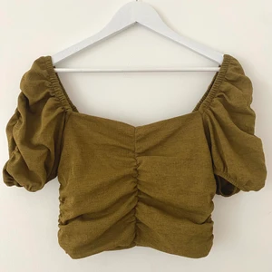 Crop-top blus  - En militärgrön söt blus från HM. Stretchigt tyg. Kan bäras både på axlarna och ”off-shoulder”. Aldrig använd. Storlek M men sitter ganska tight på kroppen, fast fortfarande bekväm då det är stretch.