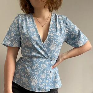 Blå mönstrad blus - Fin blå blus med vitt blommönster! Använd en gång så den är i nyskick. Har tyvärr blivit för liten för mig. Sitter fantqstiskt bra och urringningen är inte för mycket. För mer frågor eller bilder är det bara skriva ett meddelande☀️