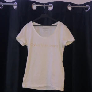 V-ringad Calvin Klein t-shirt, Strl S - V-ringad Calvin Klein t-shirt i fint skick med en stilren guld text. Strl s men skulle även passa xs. 50kr + frakt