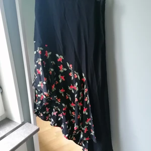 Assymetrisk kjol från H&M trend.  - Svart med körsbär. Så fin kjol som är längre på ena sidan och kortare på andra. Fint fall och härligt print. I mycket fint skick. Strl 38