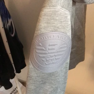 Armani kofta - Grå Armani kofta, använd fåtal gånger därmed inga defekter alls. Den är storlek L men den sitter perfekt på mig som har M. Frakten är på 66kr