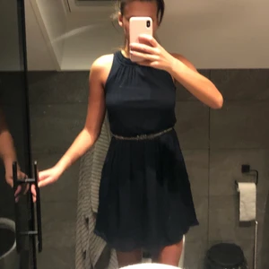 Mörkblå festklänning från Zara - En mörkblå festklänningen med glitter i midjan och knappar som man stänger med bak i ryggen. Använd några få gånger så den är i fint skick! 