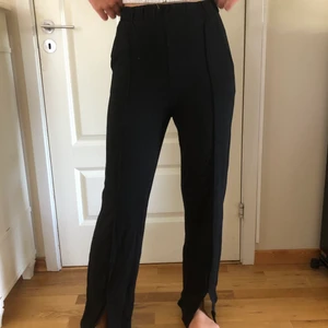 Svarta stilrena mjukisbyxor med slit - Svarta mjukisbyxor med slit framtill samt en söm längst hela benet på framsidan. Jag är 175 cm lång. Kan kläs upp och ner. Väldigt bekväma. Helt i nyskick