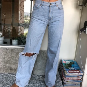 Blå jeans - Ett par blåa vida jeans med ett egengjord hål i ena knät. Bra skick och super snygga! Jag är 175cm och dom är på gränsen för korta för mig.