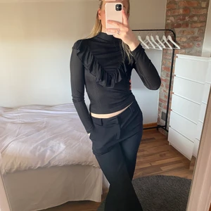 Fest topp - Säljer denna jätte fina fest top från Gina Tricot! Väldigt skön svart, lite randig i materialet/glansigt med hög hals samt volang ⚡️⚡️🤍