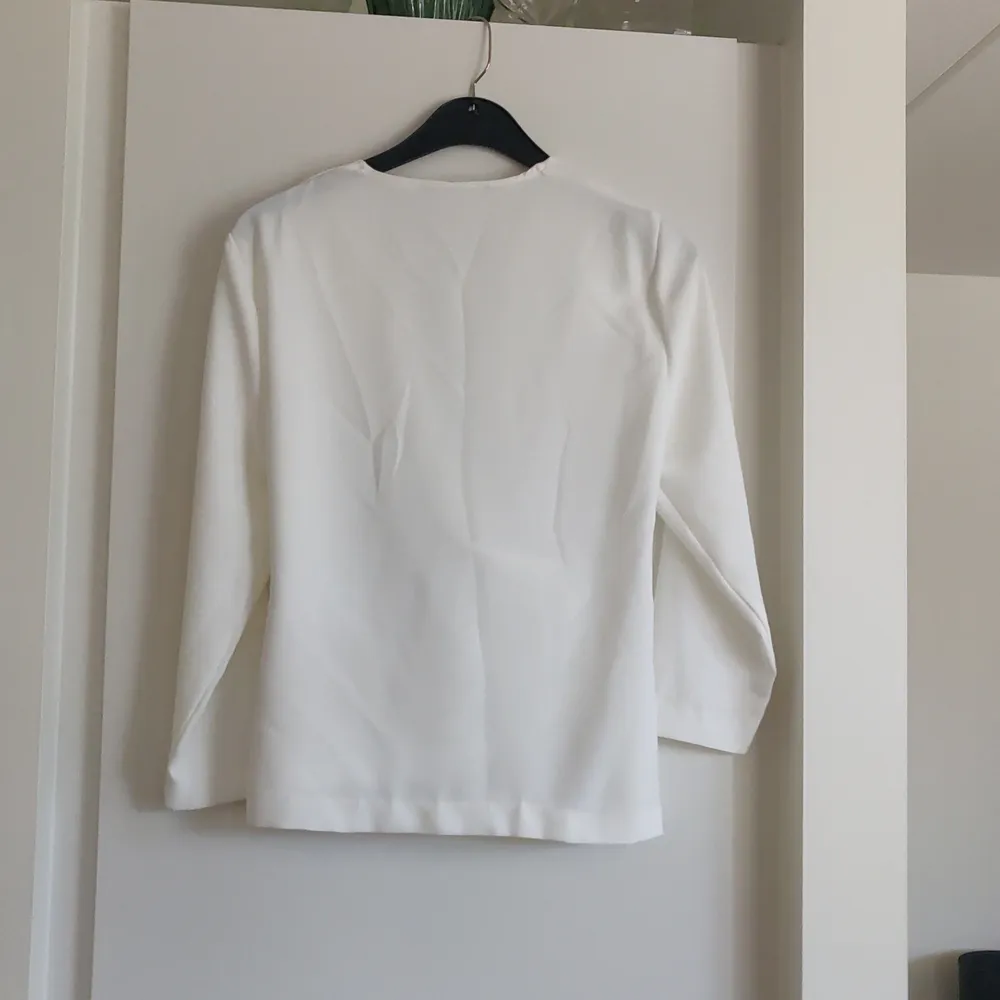 En vit blus med rynkad omlott detalj fram från Zara i storlek M. Materialet är 100% polyester. Fraktkostnaden tillkommer.. Blusar.