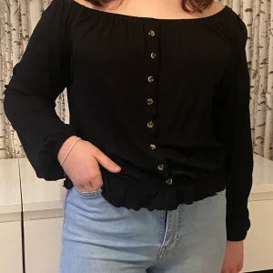 Superfin tröja strl M - Superfin svart off shoulder tröja med knappdetaljer! Använd ca 3 ggr så i jättefint skick!