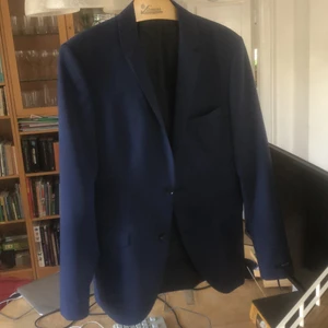 Marinblå kostym från jack and Jones.   - Kavajen är i storlek 48 och byxorna i storlek 46. Endast använd en gång och har nu vuxit ur den.      Superbra skick:).                                                            Från kavajens axelsömm till ärmslut: 62cm. Från kragtopp till kavajens slut 73 cm. Axelbredd: 41 cm.       Byxornas midjeomkrets: 82 cm. Byxornas längd: 101 cm. 