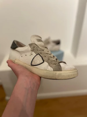 Vita Philippe Model skor - Dessa tjusiga skor passar bra nu till vårens strålande dagar. Det finns ett litet hål ungefär vid insidan av hälen på båda skorna, hålen är inte djupa och dem känns inte märkvärdigt mycket när man har på sig dem. Jag kommer inte kunna ta emot bud under 1000kr. Skriv privat vid frågor