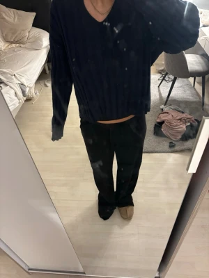 Mörkblå ribbad v-ringad tröja - Säljer en mörkblå ribbad tröja med v-ringning och långa ärmar. Tröjan har en avslappnad passform och är perfekt för dig som gillar en enkel men stilren look. Passar till det mesta och är lätt att matcha med andra plagg.