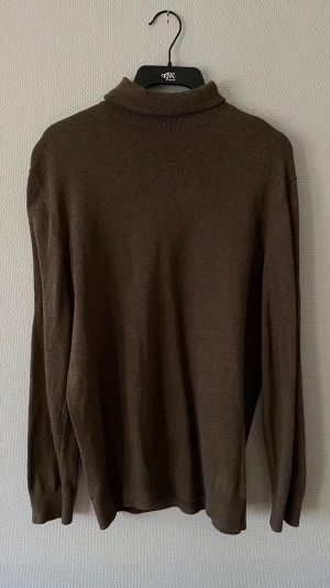 Brun stickad tröja H&M - Mjuk och stilren brun stickad tröja från H&M i slim fit-modell. Tröjan har rund halsringning och långa ärmar, perfekt för lager på lager. Enkel design som passar till det mesta och är lätt att matcha.