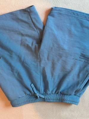 Blå pyjamas från Mackenzie - Säljer en blå pyjamas från Mackenzie med tryck på tröjan. Setet består av långärmad tröja och byxor med resår och knytband i midjan. Materialet är mjukt och skönt, perfekt för att chilla hemma.