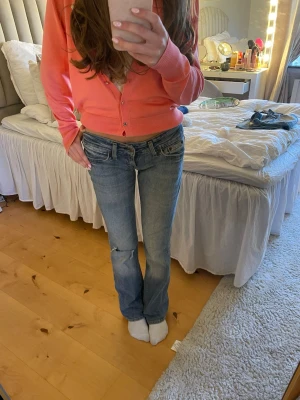 Blå bootcut jeans från Lee - Säljer ett par ljusblå bootcut jeans från Lee med låg midja och slitna detaljer. Storlek W26 L33.