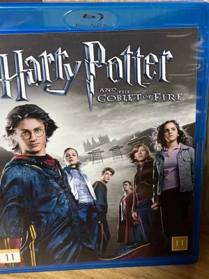 Harry Potter and the Goblet of Fire Blu-ray - Blu-ray-utgåva av filmen 'Harry Potter and the Goblet of Fire' med blå plastfodral och omslag i svartvitt med karaktärer från filmen. Text på svenska, engelska och flera andra språk på baksidan. Perfekt för samlare eller Harry Potter-fans.