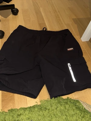 Svarta shorts från MCKENZI - Säljer ett par svarta shorts från MCKENZI med praktisk dragkedja på ena benet och fickor på sidorna. Använd fåtal gånger, ingen täcken på användning. Säljer för det är för stora för mig. 