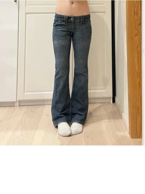 Mörkblå bootcut jeans med fickor - Snygga mörkblå bootcut jeans med låg midja och framfickor. Jeansen har klassiska bakfickor och vita sömmar som kontrast. Perfekta för en avslappnad och trendig look. Materialet är denim i bomull. Midja 41, innerben 81, gren 18,5 💞