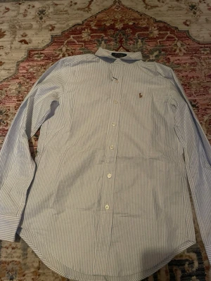 Randig skjorta från Polo Ralph Lauren - Randig raffe skjortan! As fet å passar perfekt till sommaren.  Tyvärr  passar inte den mig så släpper för billigt då jag fick den som present!!! FÖRST TILL KVARN 250 KRONER!