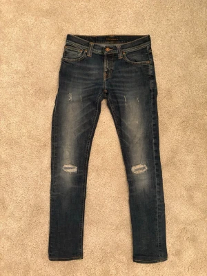 Nudie Jeans - Nudie jeans med snygga slitningar i storlek w27 l32. Modell tight long John det är killmodell. 