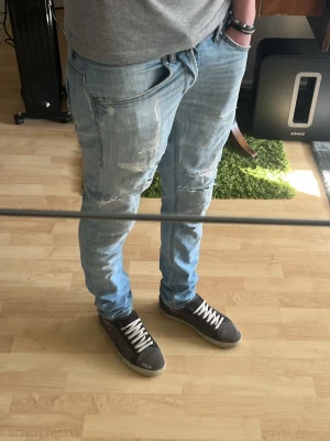 Ljusblå dondup jeans med snygga slitningar - Ett par ljusblå dondup jeans med schysta slitningar. Perfekta inför sommaren. De är använda men är fortfarande i bra skick. Modellen är 183cm och väger 65kg. Midja: 40cm, innerben: 77.5cm, ytterben: 102cm. Är öppen för frågor och funderingar💫