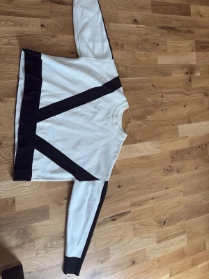Vit tröja med svarta detaljer  - En vit tröja med svarta detaljer, märke är lite oklart men den är i storlek XS, Säljer då jag inte tyckte om hur den passa på mig. Annars är den jätte fin. Använd 1 gång då jag provade den annars är den helt oanvänd.💕