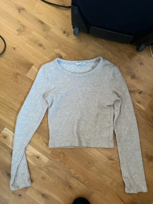 Beige croppad tröja Gina Tricot zara - Beige croppad tröja från zara med rund halsringning och långa ärmar. Tröjan är enkel och stilren, perfekt att matcha med jeans eller kjol. Materialet känns mjukt och stretchigt, vilket gör den bekväm att bära hela dagen.