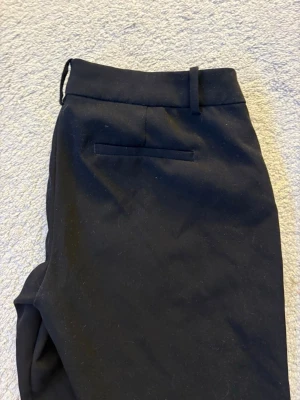 Svarta kostymbyxor med raka ben - Snygga svarta lågmidjade kostymbyxor med raka ben och enkel bakficka från bikbok. Använd ett par gånger men dom är inte noppriga eller sönder nånstans. Säljer dessa pågrund av att dom är för korta i benen och för liten i midjan