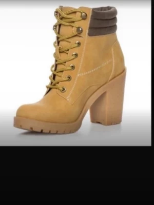 Gula stövletter med klack och snörning - Snygga stövletter i gul mockaimitation med kraftig klack och grov sula. Skorna har snörning framtill med guldfärgade öljetter och vadderad brun kant upptill för extra komfort. Perfekta för dig som vill ha en cool och trendig look.