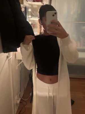 Vit lång stickad kofta - Säljer min vita stickade kofta som är till mina knän, jag är 159. Den är i väldigt bra skick skulle jag säga har använt den ett par gånger och det går att passa ihop med flera olika outfits.