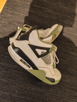 Nike Air Jordan 4 vita och gröna - Säljer ett par Nike Air Jordan 4 sneakers i vitt, grönt och svart. Skorna har meshdetaljer på sidorna, gröna accenter och klassisk hög siluett med synlig Air-sula. Perfekta för dig som gillar streetwear och ikoniska modeller. De är äkta då de köptes på S&C Hype på A6 Center. De är i storlek 41 