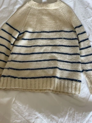 Vit stickad tröja med marinblå ränder - Klassisk stickad tröja i mjuk vit ull med tunna marinblå horisontella ränder. Fint skick! Storlek XS/S