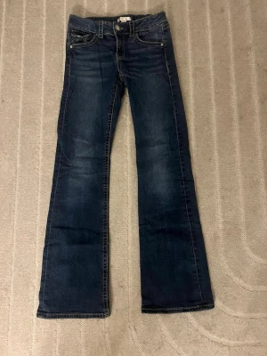 Mörkblå bootcut jeans från gina  - Säljer ett par mörkblå bootcut jeans från gina tricot. Med klassisk femficksdesign och kontrastsömmar. Bakfickan har ett litet hål eller tyget har töjts ut (går säkert att laga) storlek 164