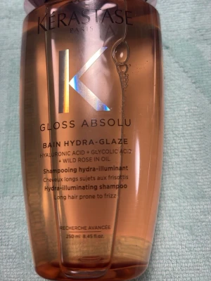 Kérastase Gloss Absolu Hydra-Glaze - Kérastase Gloss Absolu Bain Hydra-Glaze är ett glansgivande schampo med hyaluronsyra, glykolsyra och vildrosolja. Flaskan är genomskinlig med rosatonad vätska och rymmer 250 ml. Perfekt för långt hår som lätt blir frissigt.