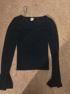 Svart långärmad topp från Gina Tricot - Snygg svart långärmad topp från Gina Tricot, kollektionen Elevated Basics. Toppen har en figurnära passform och en bred, något fyrkantig ringning. Perfekt att styla med jeans eller kjol för en trendig look.