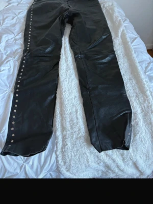 Svarta jeans med nitar längs benen - Coola svarta skinnbyxor i äkta läder,med nitar på sidorna. Passar perfekt till att köra MC