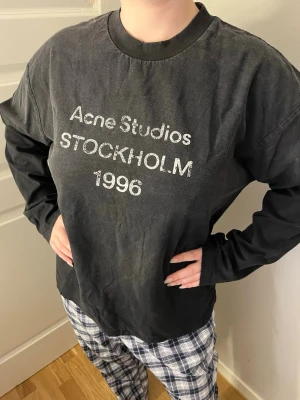 Svart Acne Studios storlek S  - Svart Acne Studios long sleeves i storlek. Svart tvättad look med vit “Acne Studios Stockholm 1996” text framtill. Mjukt och skönt material med oversized/relaxed fit. Perfekta för en clean streetwear look.  Skick: väldigt fint skick Passform: unisex Storlek: S